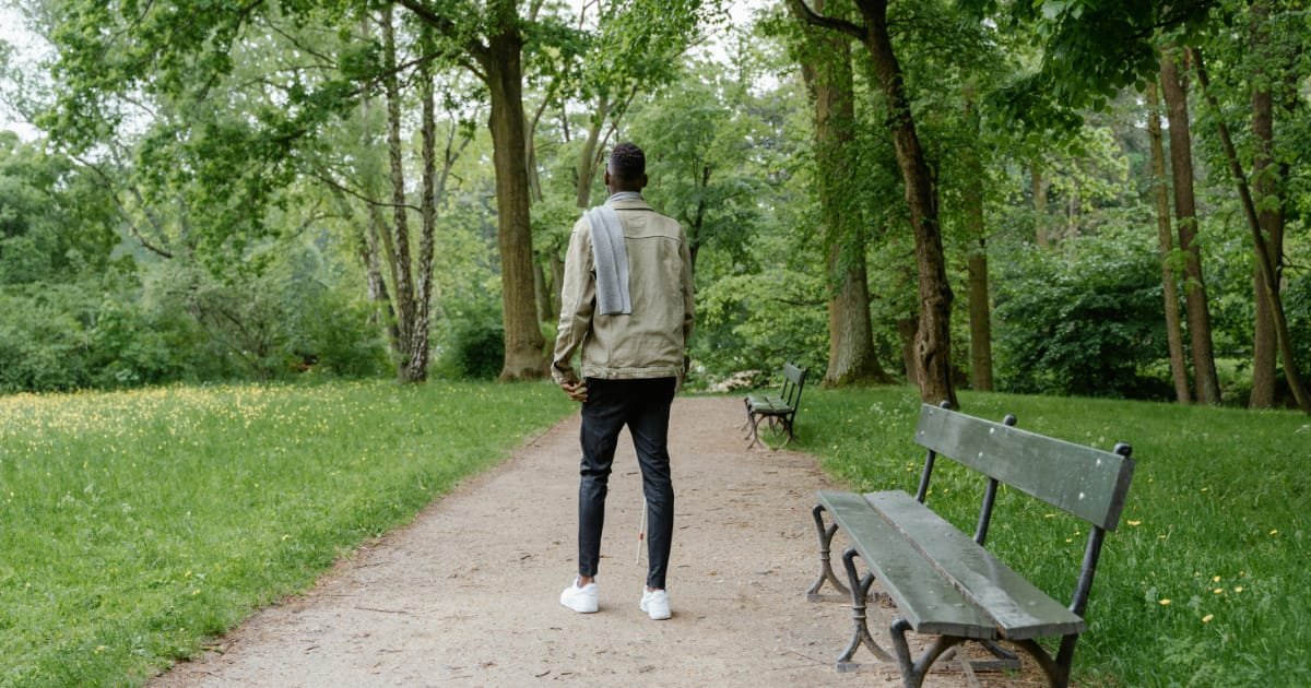 Man walking alone in a park as part of a daily walking routine