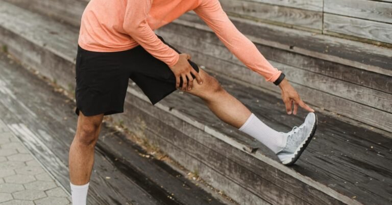 Man over 40 doing a standing hip flexor stretch in a living room as part of a daily stretching routine