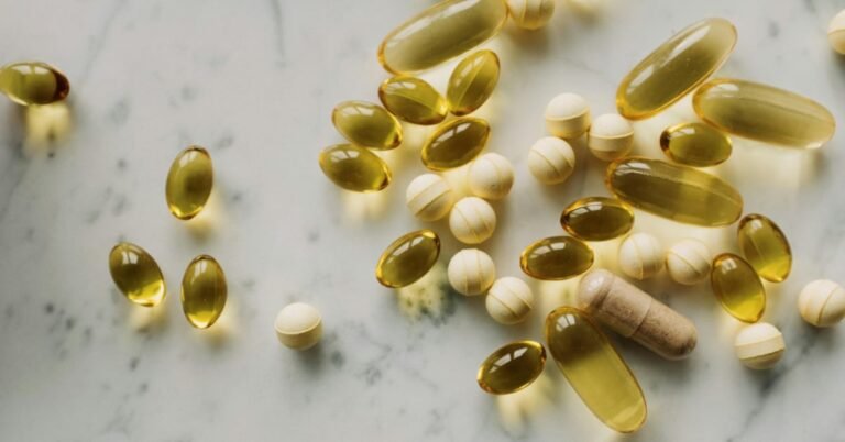 Simple supplement bottles of vitamin D, magnesium and fish oil on a kitchen counter next to whole food ingredients