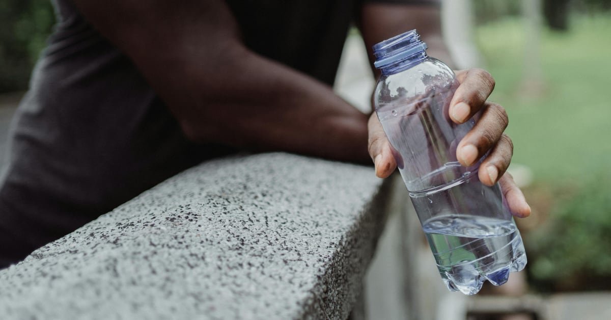 Man over 40 drinking a glass of water in a kitchen as part of a daily hydration routine