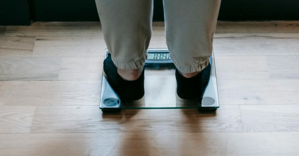 Man over 40 standing on a bathroom scale checking his weight loss progress in the morning