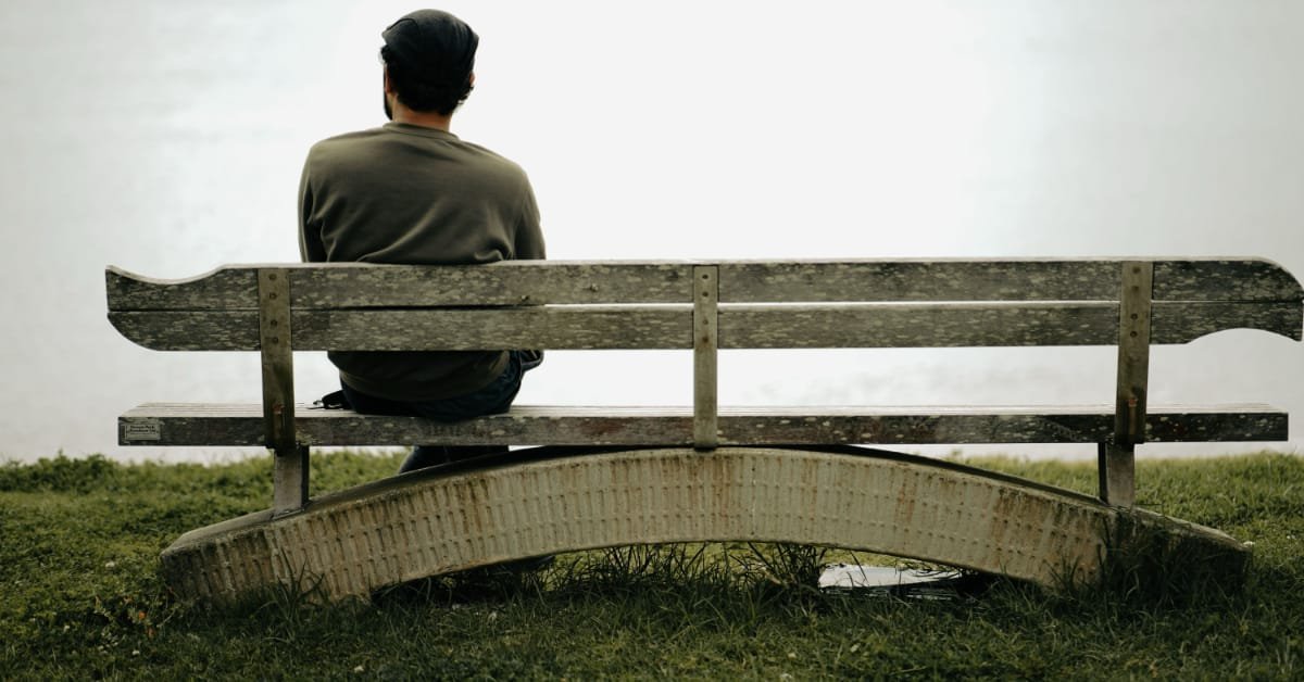 Man over 40 sitting quietly outdoors, reflecting on mental health and wellbeing in midlife