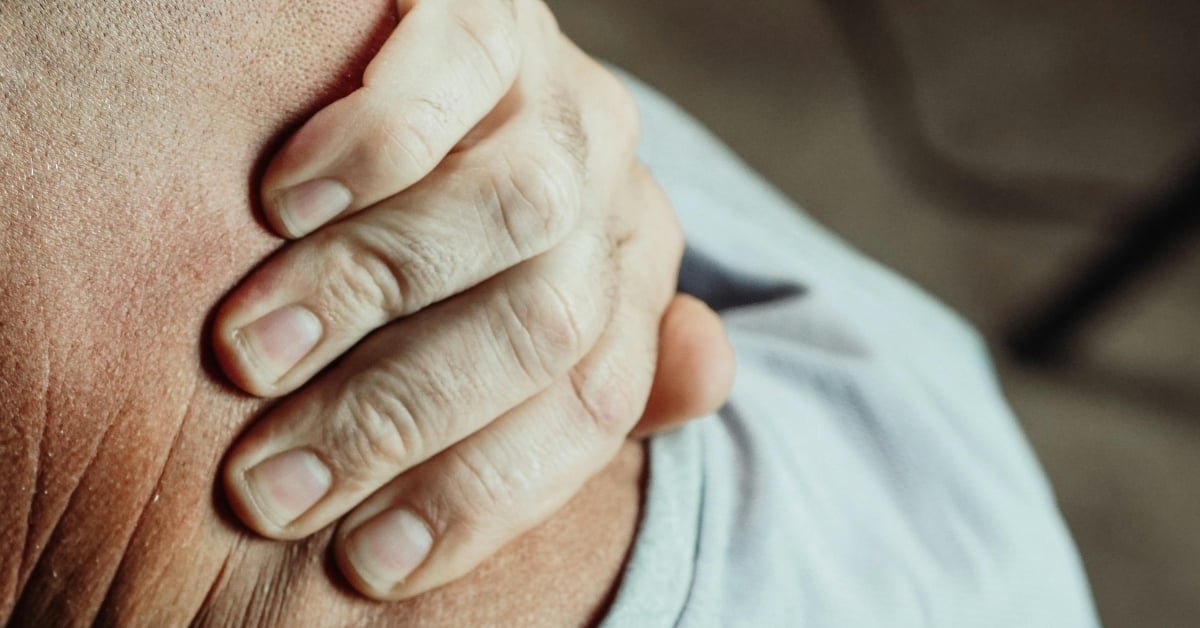 Man over 45 stretching his neck and back at a home desk after long hours of sitting