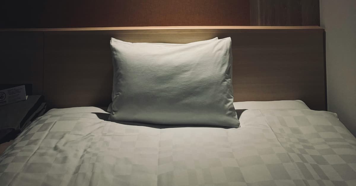 Dark bedroom with clean bed setup for better sleep after 40