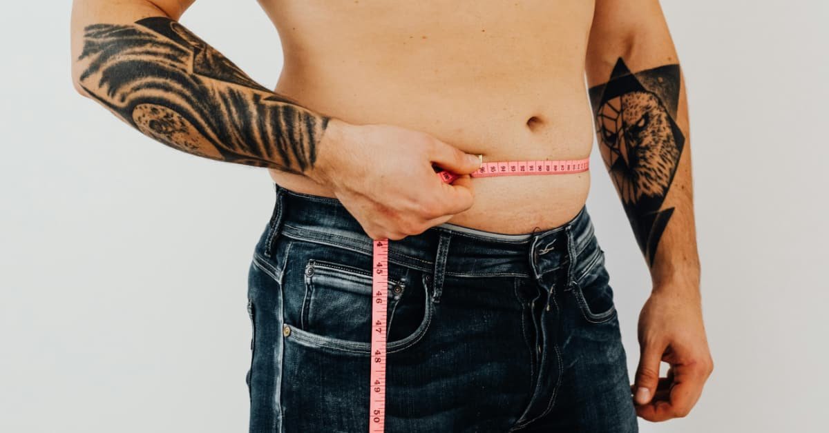 Man over 40 measuring his waist circumference with a tape measure to check for visceral fat
