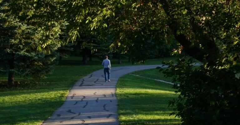 Man in his early 40s walking on a shaded neighbourhood path as part of a daily walking routine for weight loss