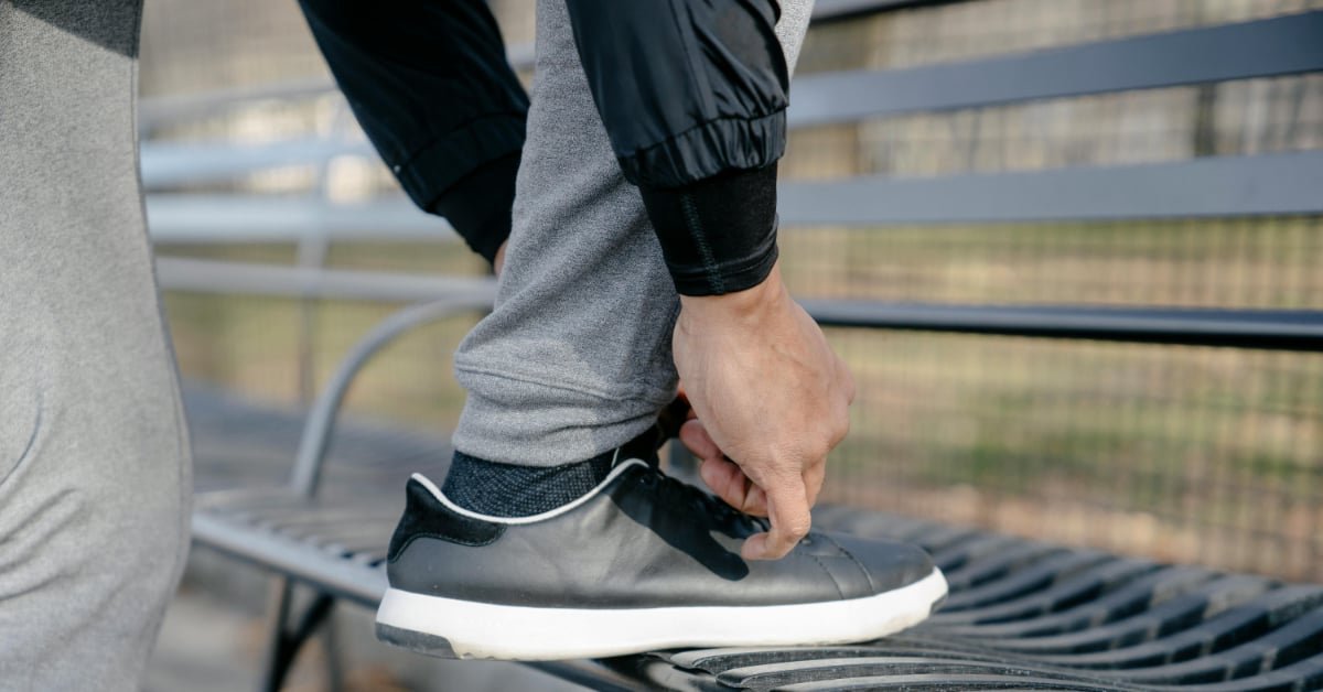 Man in his early 40s lacing up walking shoes in the early morning to resume his daily routine