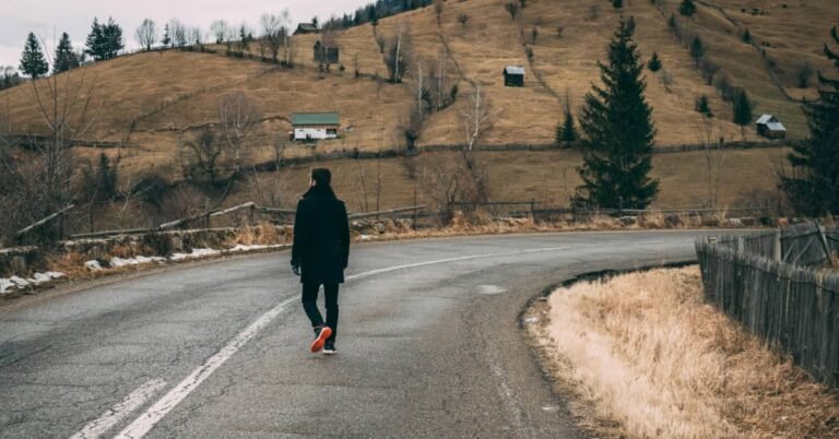 Man in his 40s walking outdoors on a quiet path, looking relaxed and focused